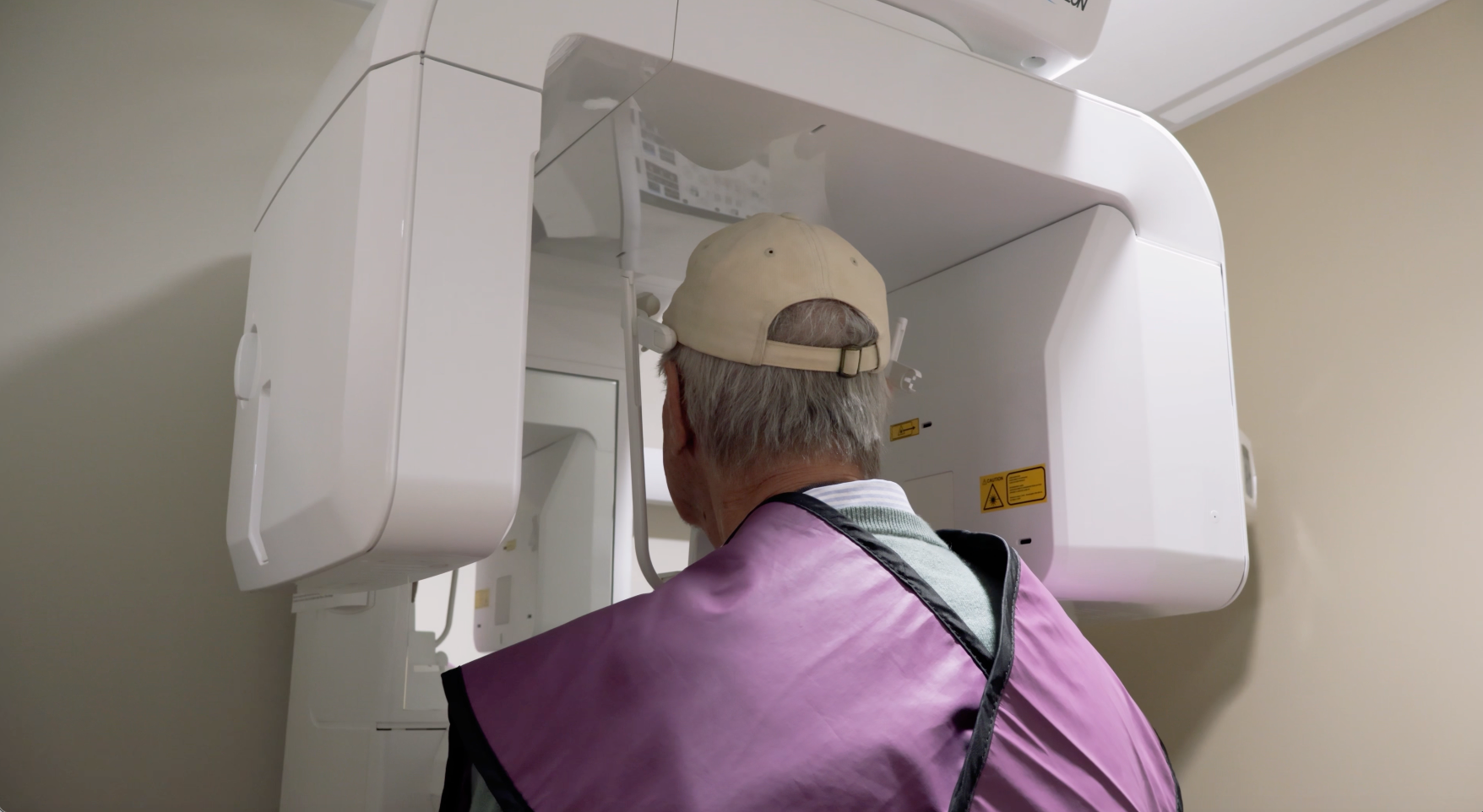 Woman in dental chair getting a panoramic X-ray, doctor adjusting machine.