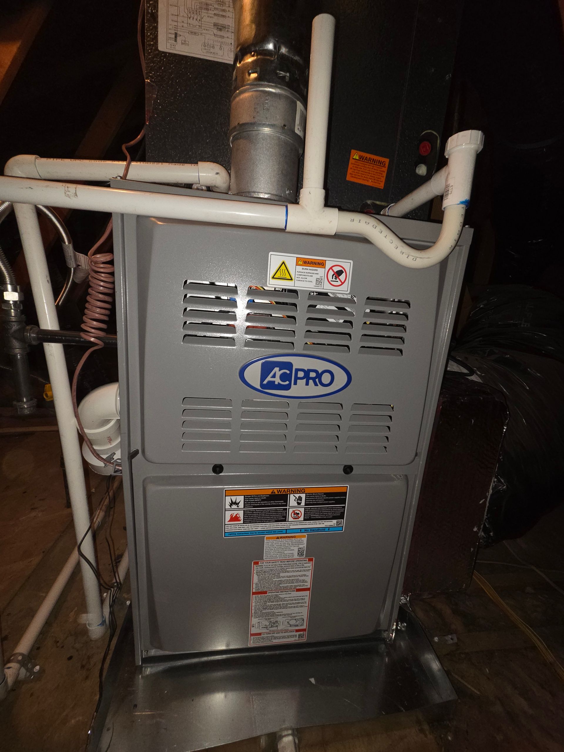 Gray APMO furnace with white pipes and venting in a basement or utility room