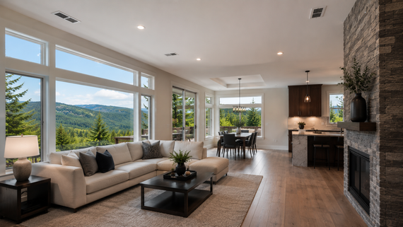 Modern open-concept living room with sofa, fireplace, dining area, and large windows overlooking hills