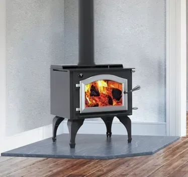Black wood stove with fire burning on a slate hearth in a bright room
