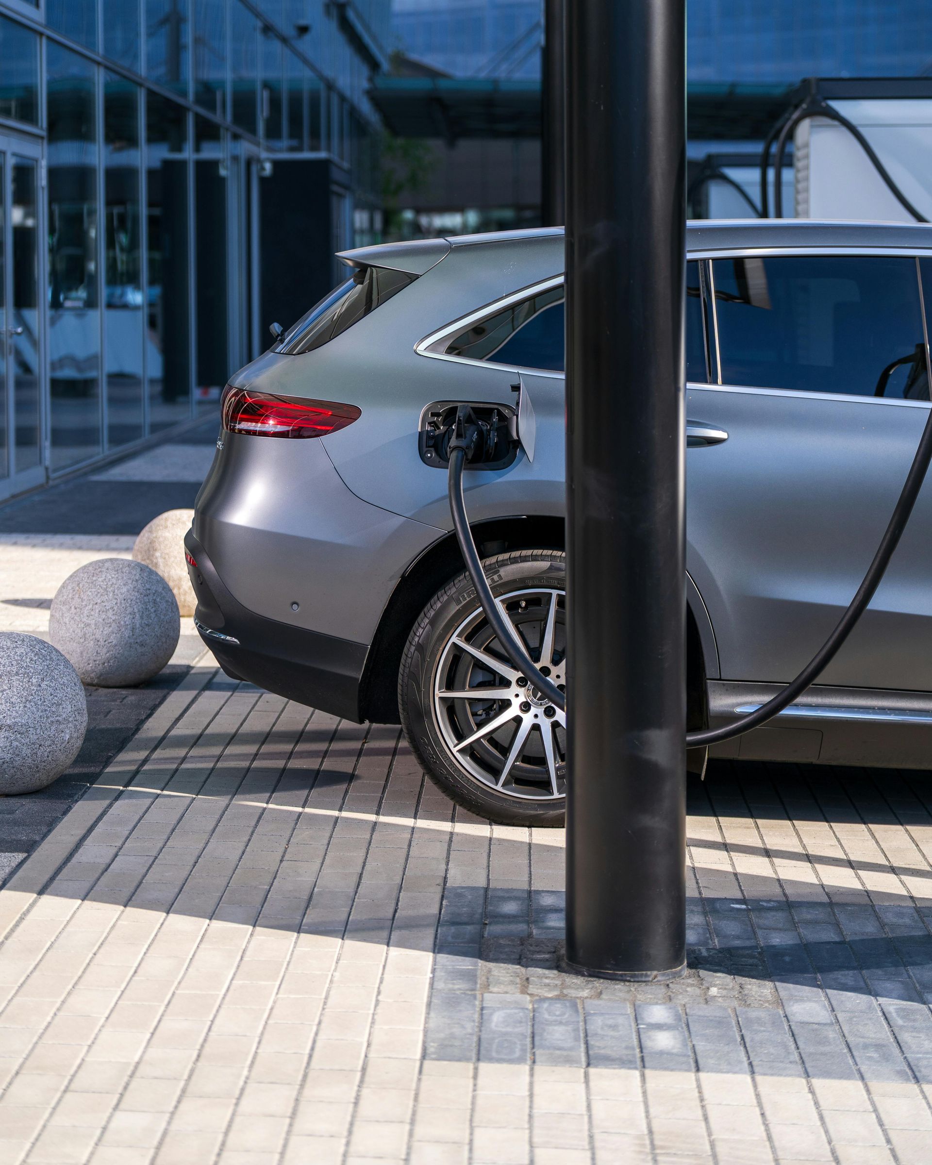 Silver SUV parked outside a modern glass building, partly blocked by a black pole