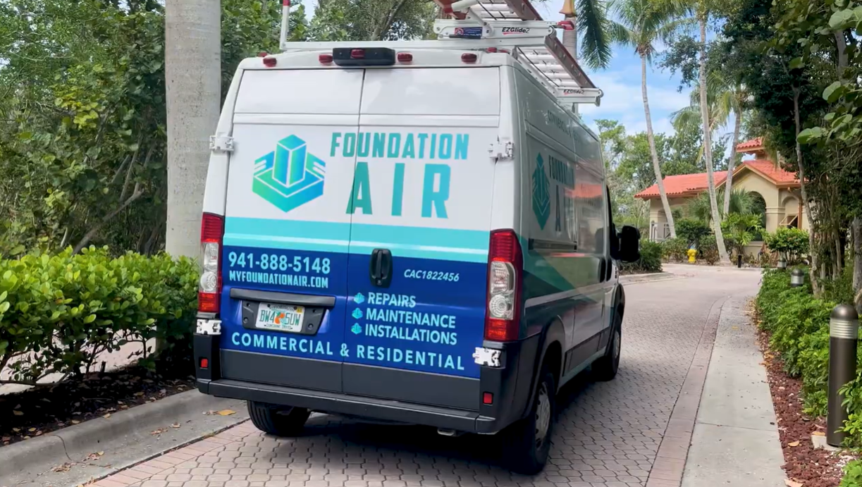 Foundation Air service van parked on a brick path beside palm trees and houses.