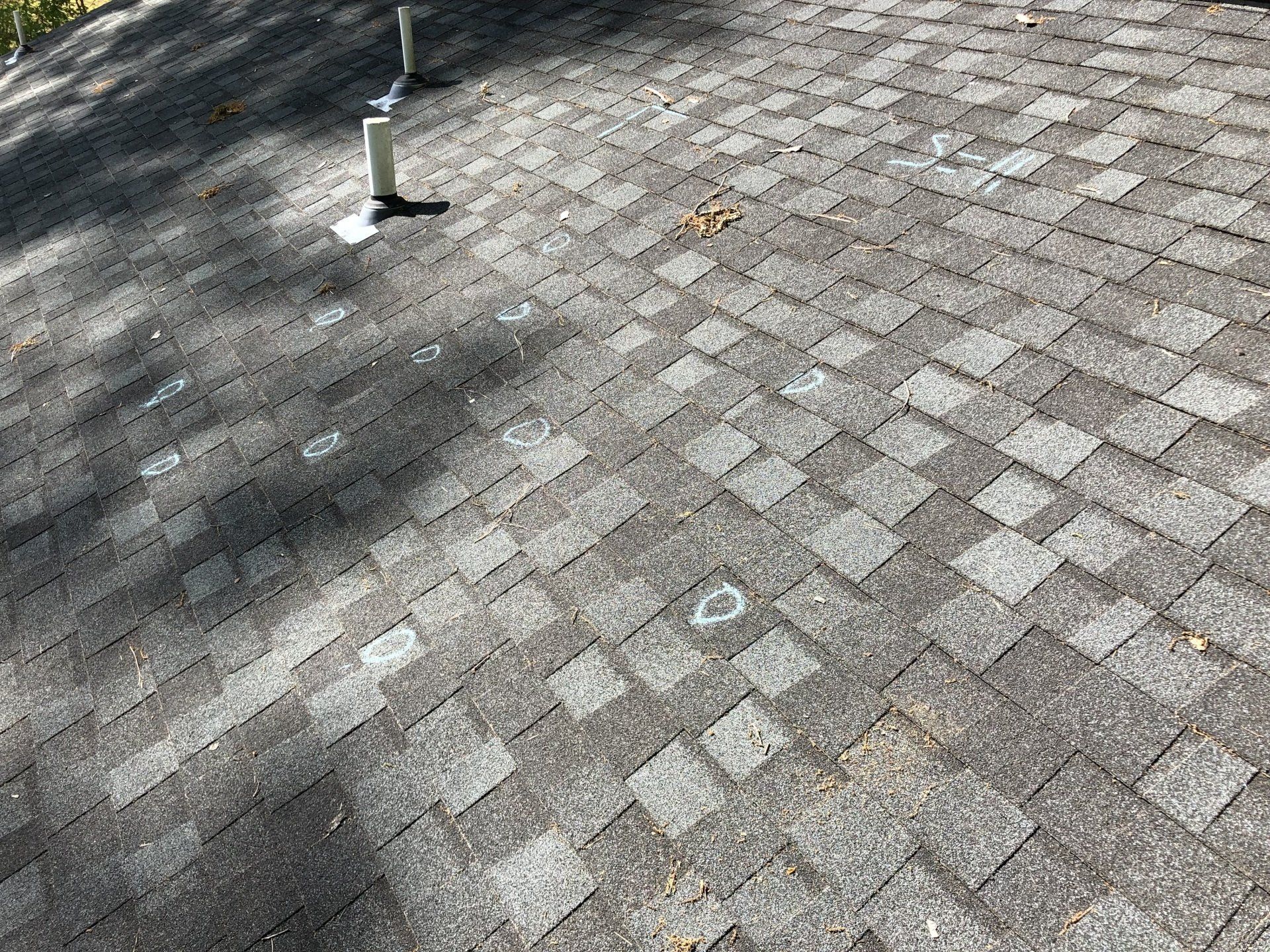A photo of an old roof marked with chalk circles, signifying hail damage.