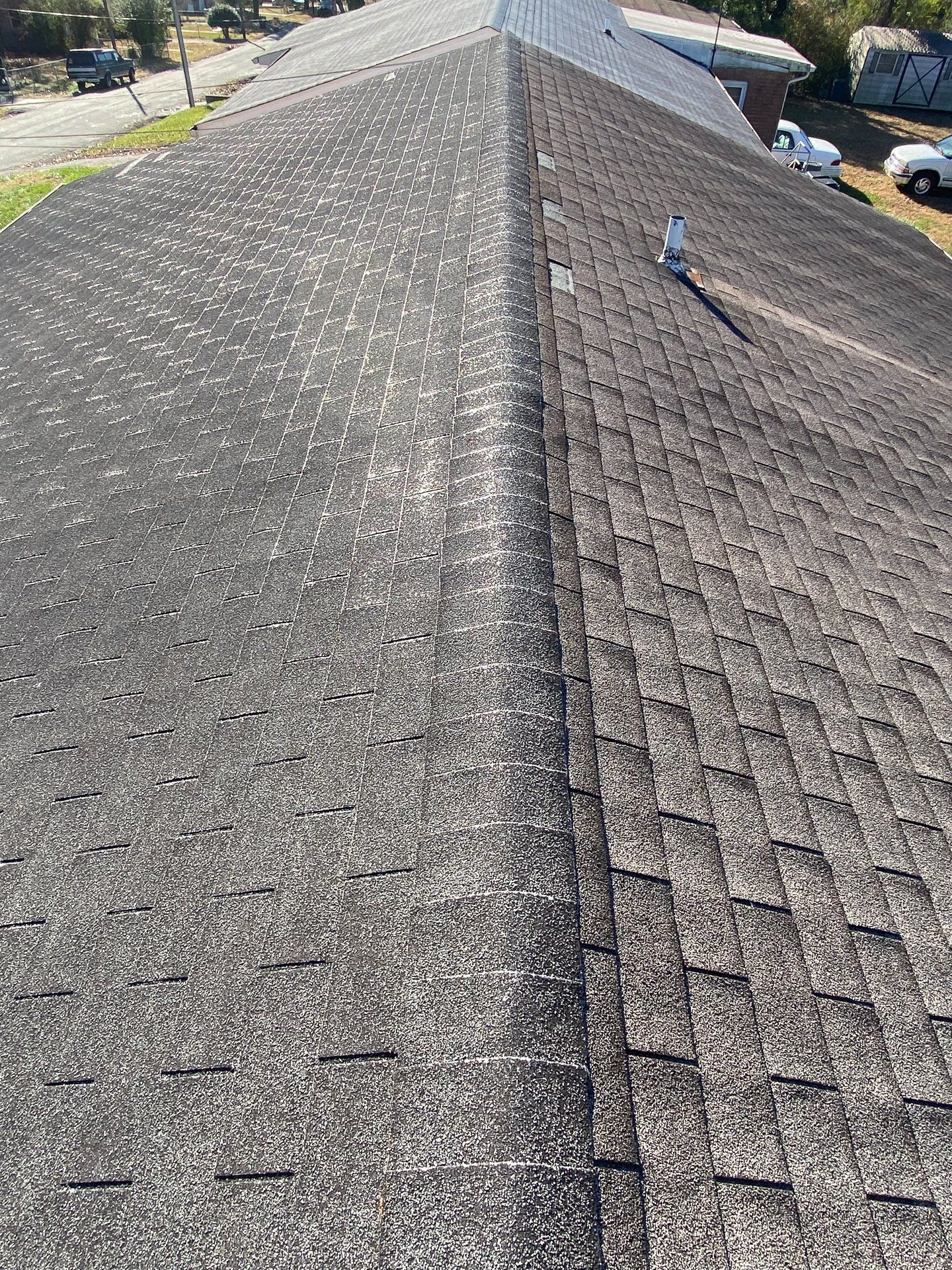 Close-up image of old asphalt shingle roof, viewpoint along the ridgeline.