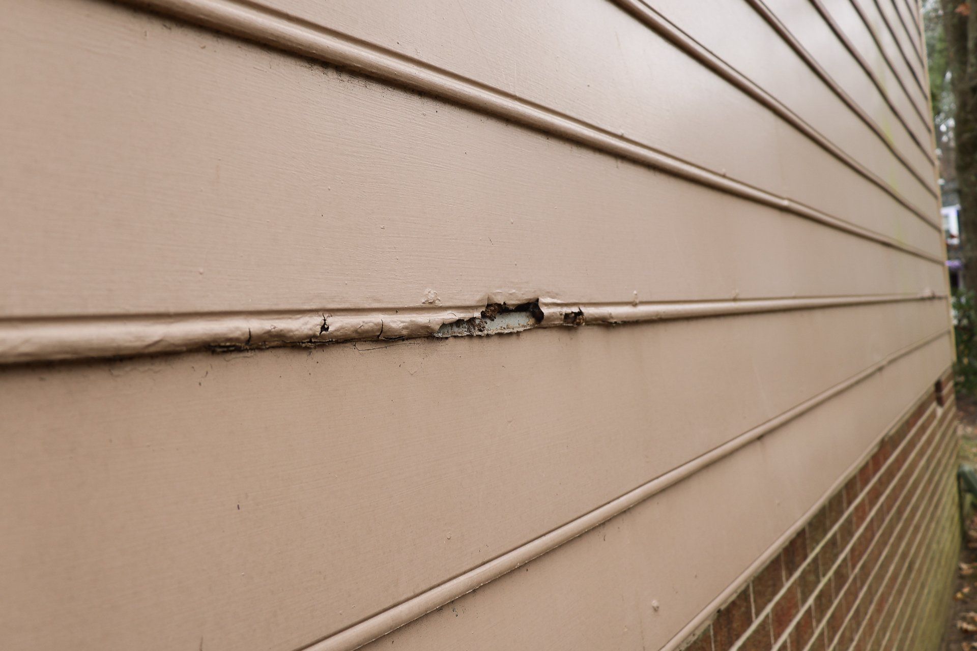 A close-up image of a damaged Masonite siding on a North Chesterfield VA home.