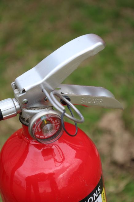 Red fire extinguisher with silver handle and pressure gauge.