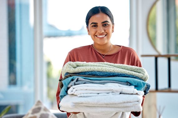 Woman holding a stack of folded towels in a bright room
