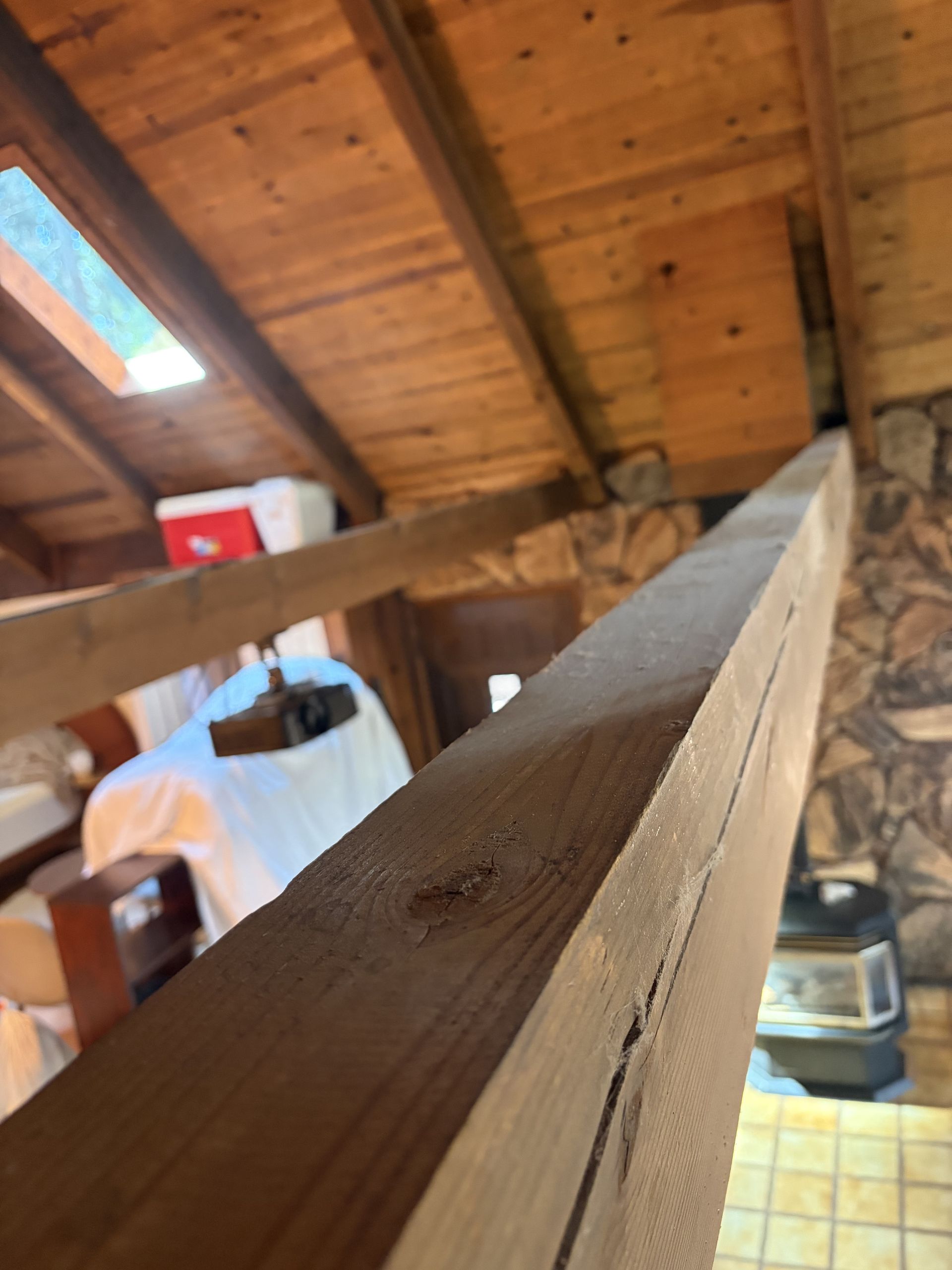 Wooden attic beams and sloped ceiling with a skylight, viewed from inside a rustic loft.