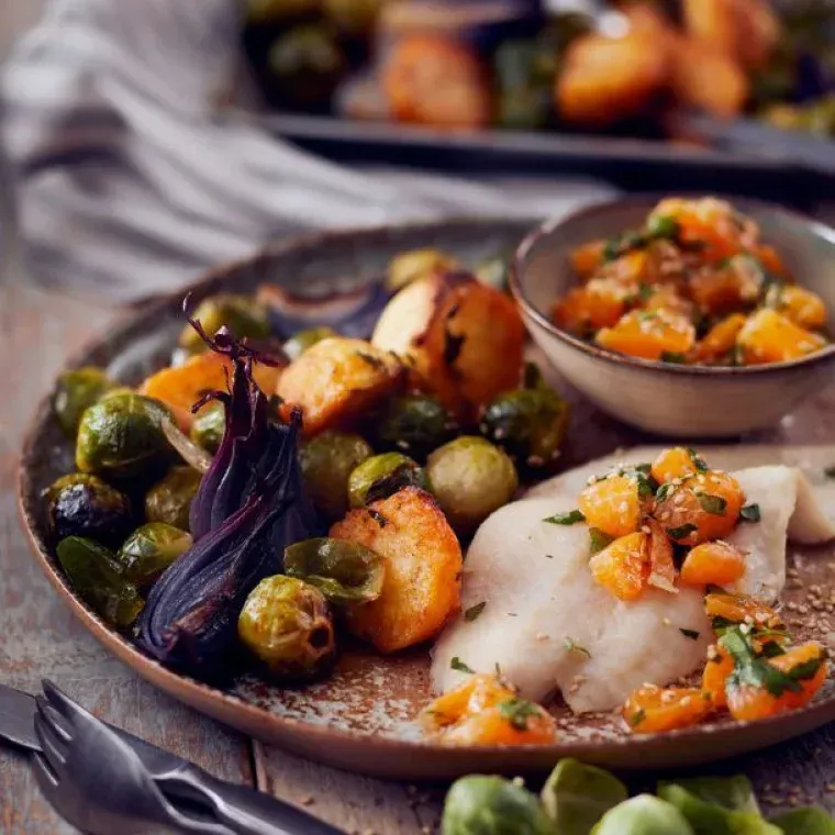Een bord met eten met groenten en vis op een tafel van lokale streekproducten menu