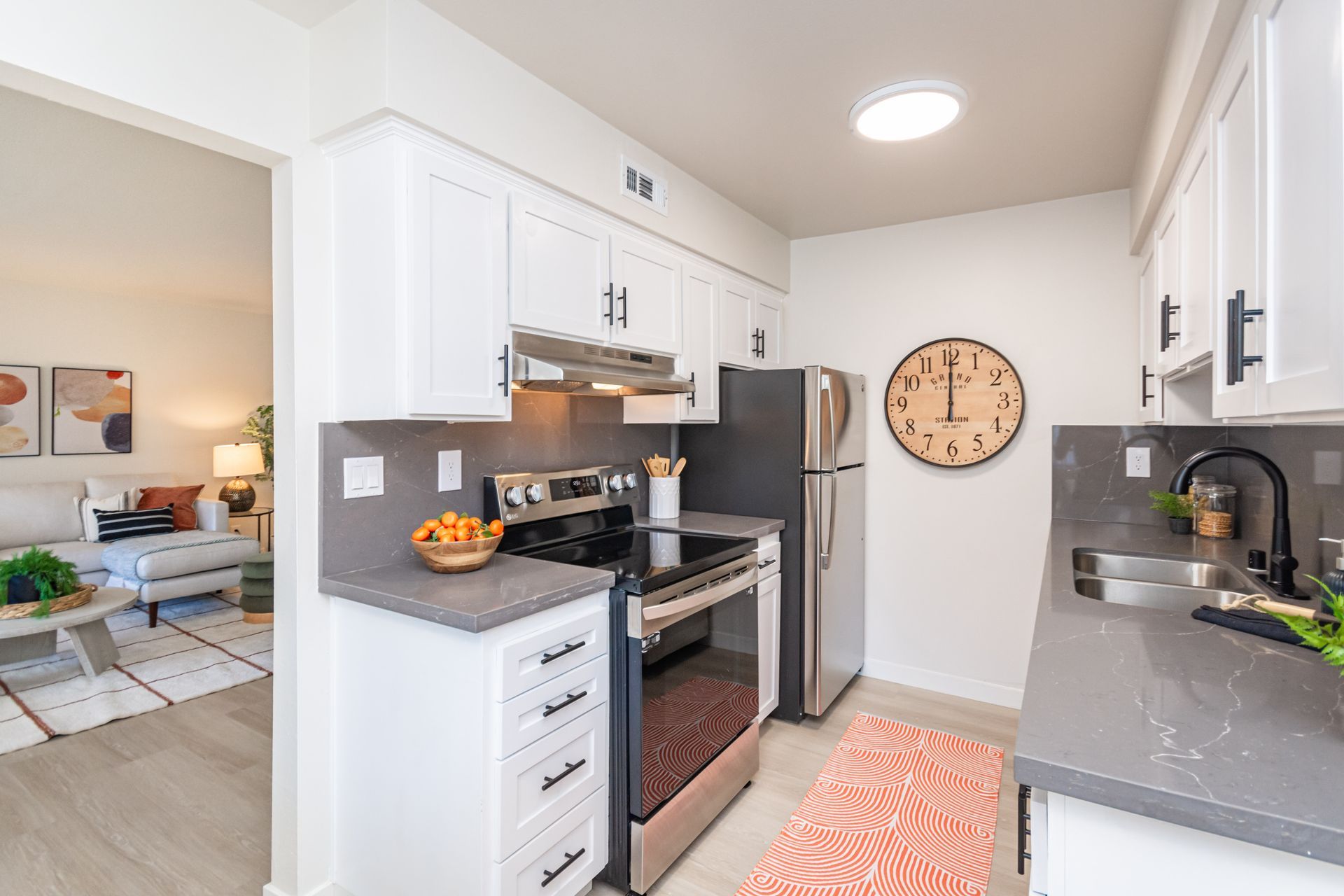 Bright white galley kitchen with stainless appliances, gray countertops, and a pink runner rug