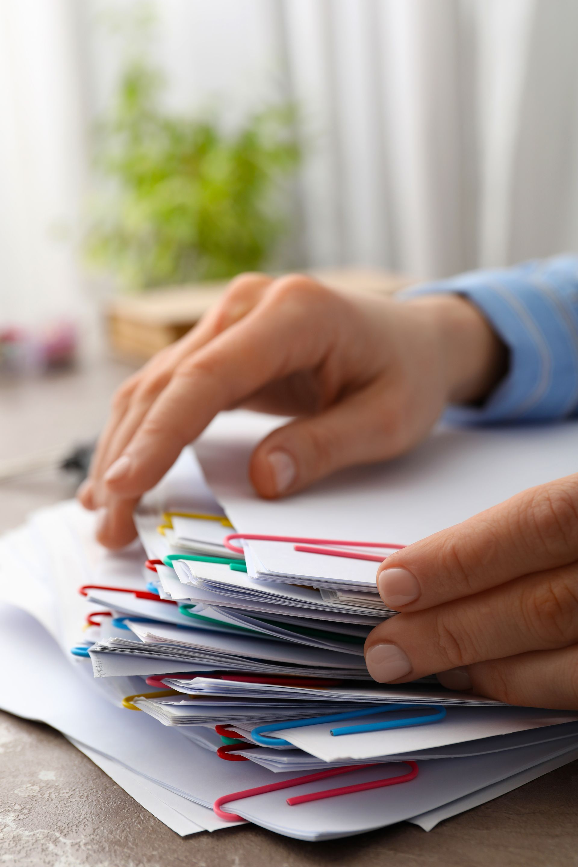 Hands sorting a stack of colorful papers on a desk