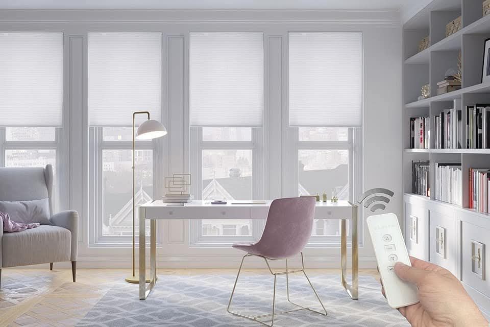 White motorized roller shades next to gray chair and desk.