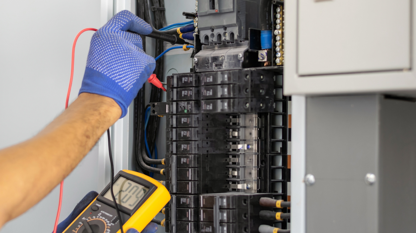 Technician in blue gloves testing electrical panel wiring with a multimeter