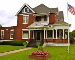 Brick house with white porch, green lawn, and American flag by the front entrance