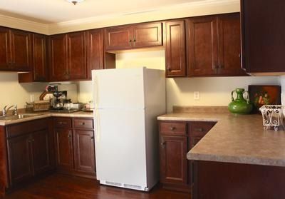 Small kitchen with dark wood cabinets, white refrigerator, and beige countertops.