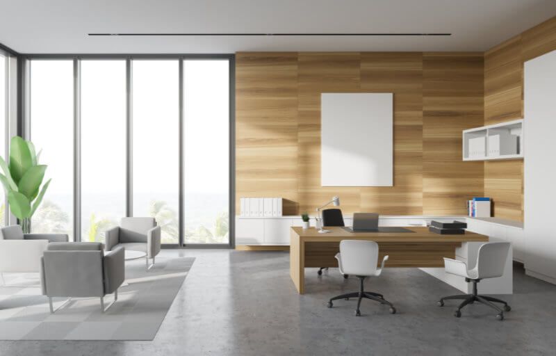 A modern office with wooden walls , a desk , chairs and a large window.