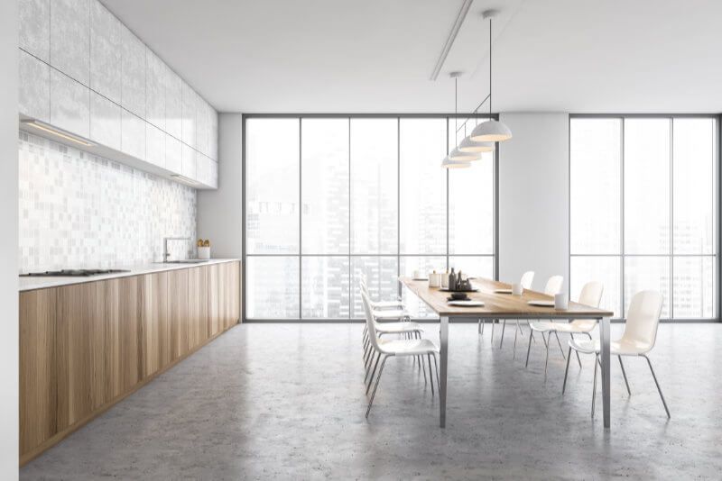A kitchen with a long table and chairs and a large window.