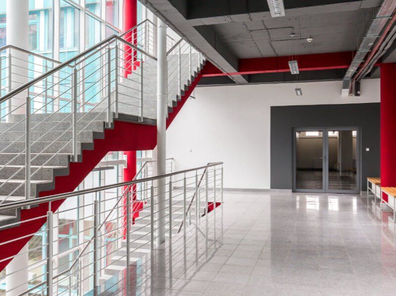 An empty hallway with stairs and a red railing