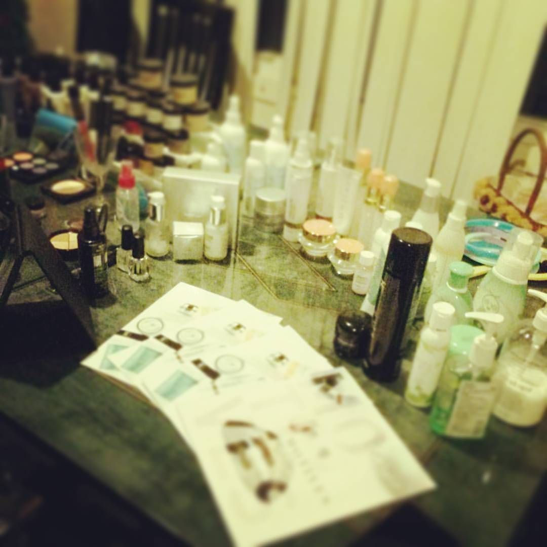 A table with various skincare products and printed papers, likely a beauty setup.