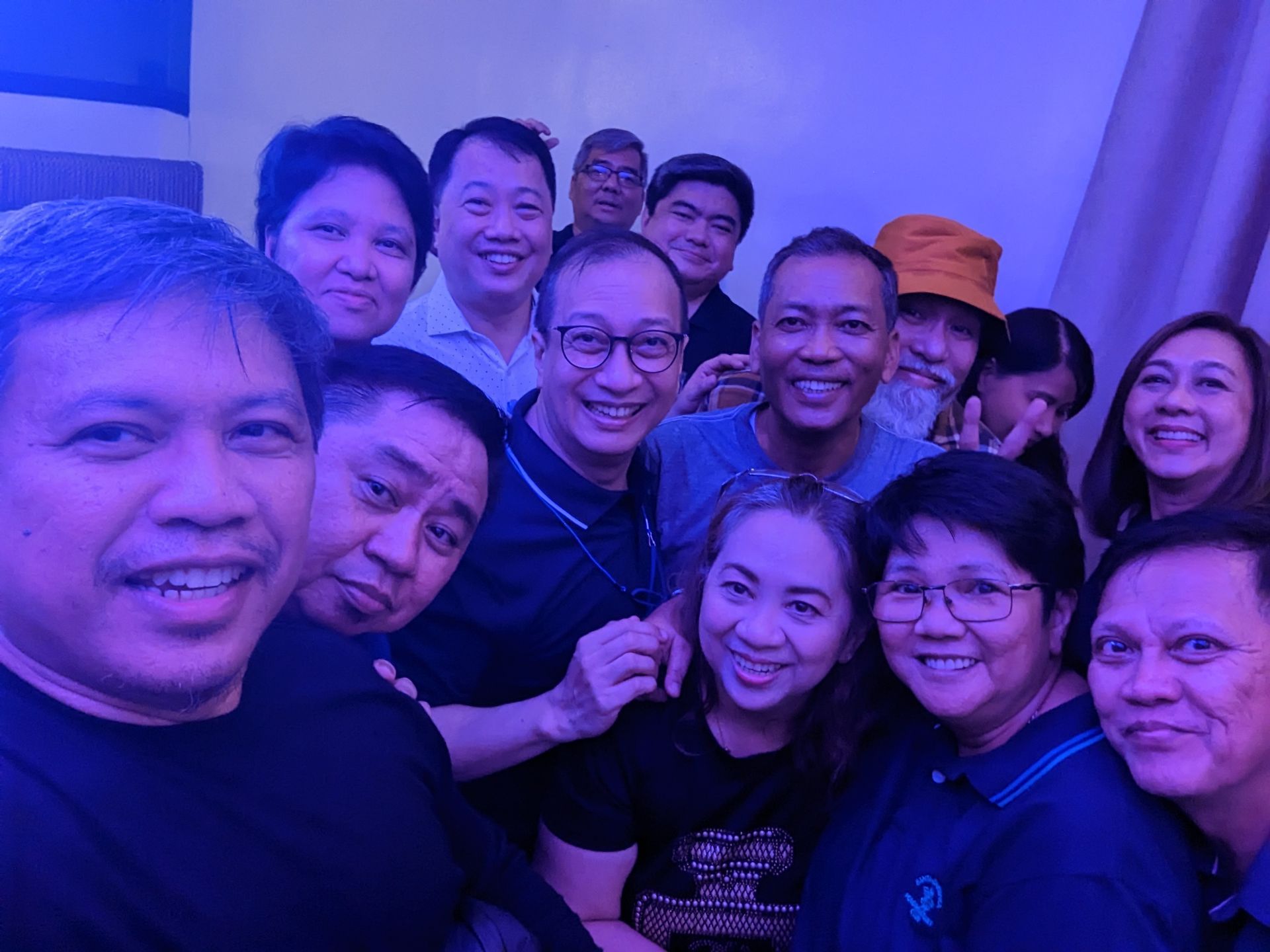 Group of people smiling, illuminated by blue light.
