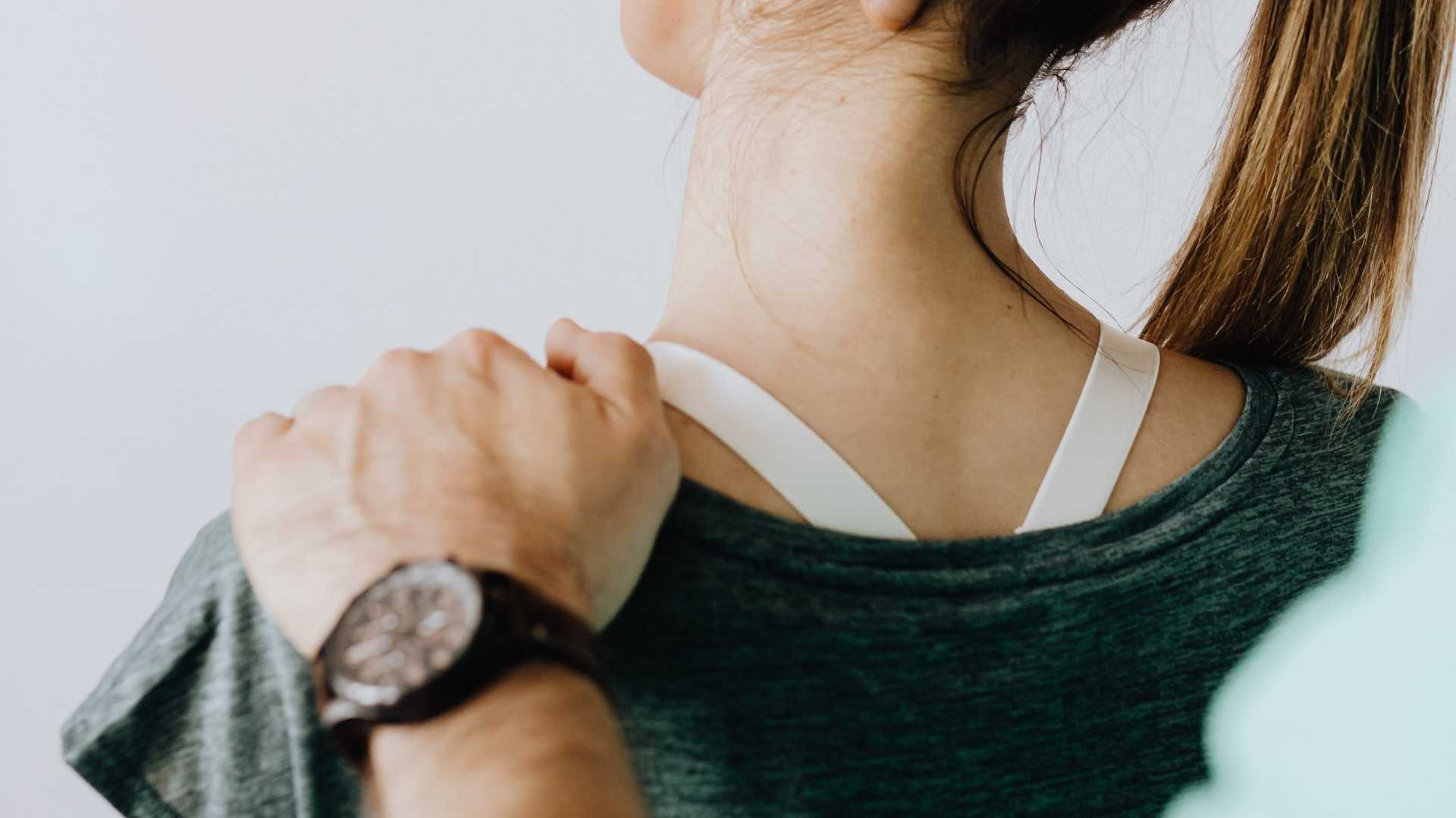 a woman wearing a watch is holding her shoulder .
