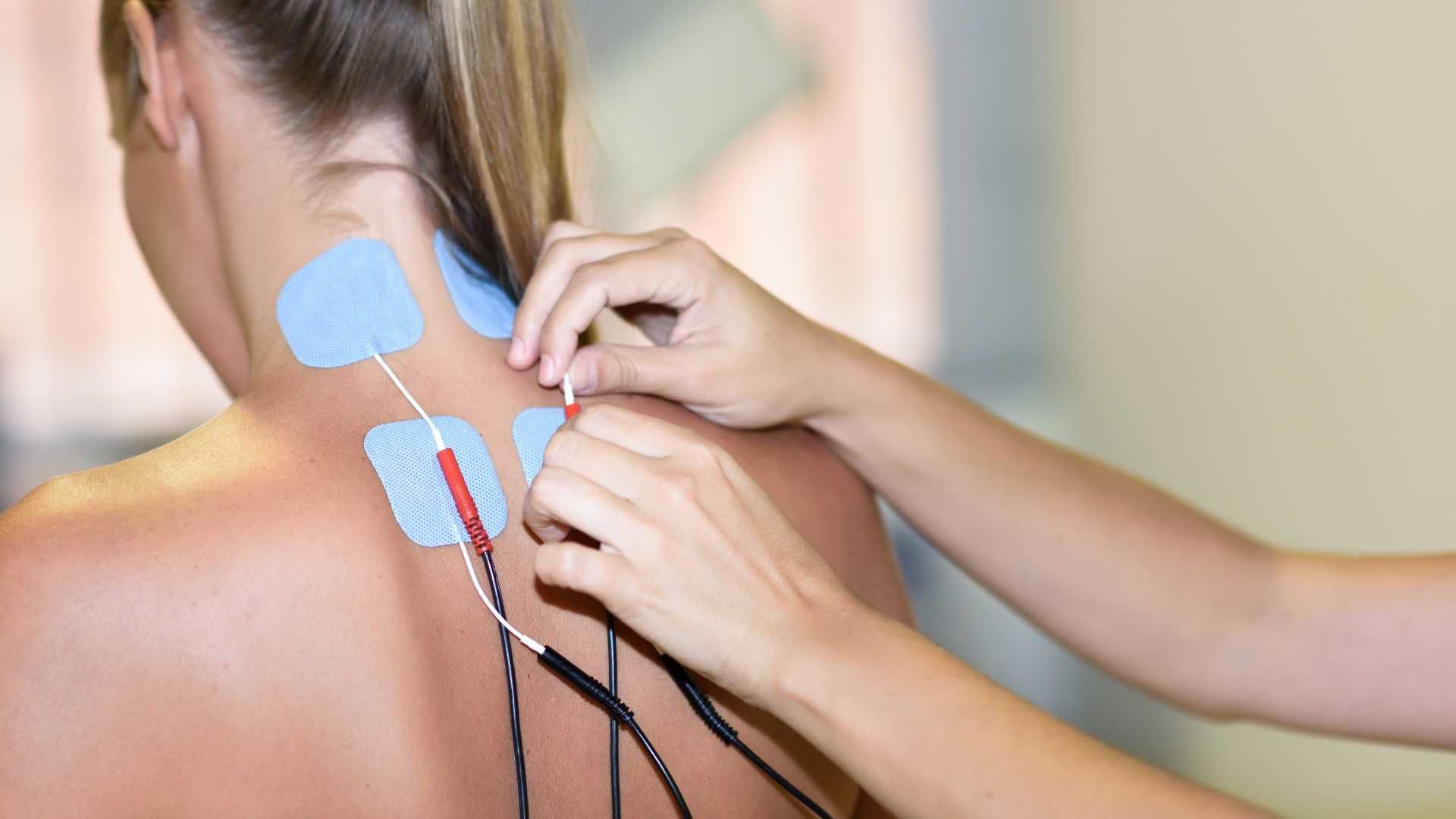 a woman is getting a massage with electrodes on her neck .