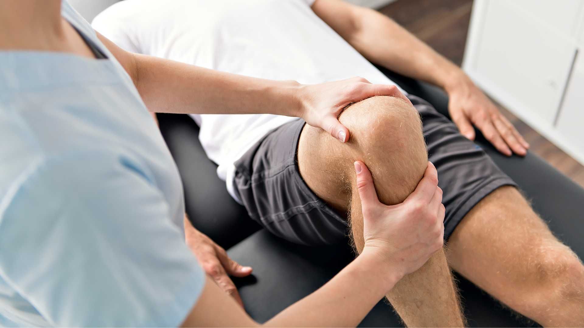 a man is getting his knee examined by a nurse .