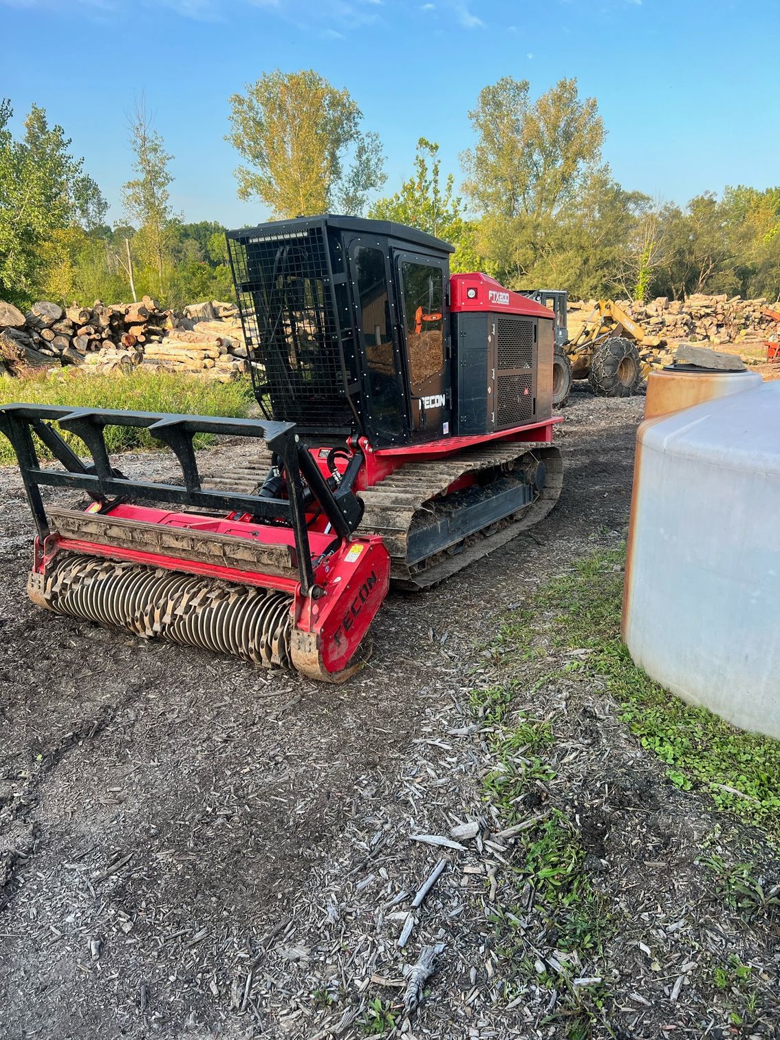 Red and black forestry mulcher on tracks, outside.