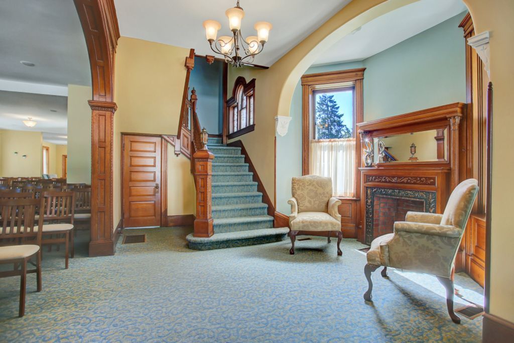 A living room with stairs , chairs and a fireplace
