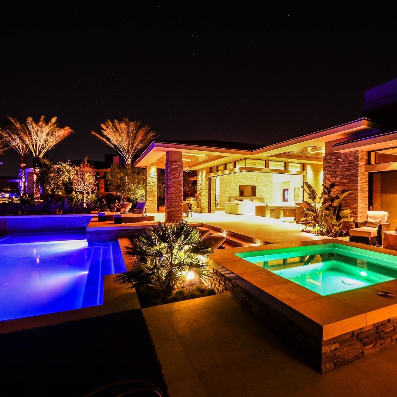 A house with a swimming pool and a hot tub at night