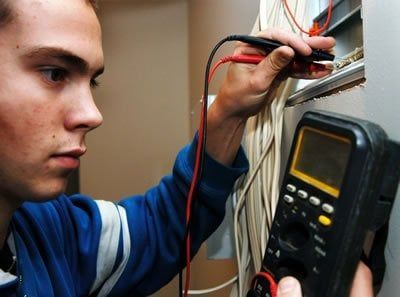 A man is using a digital multimeter to test a wire