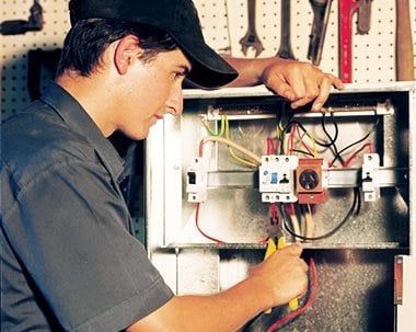 A man is working on an electrical box with pliers.