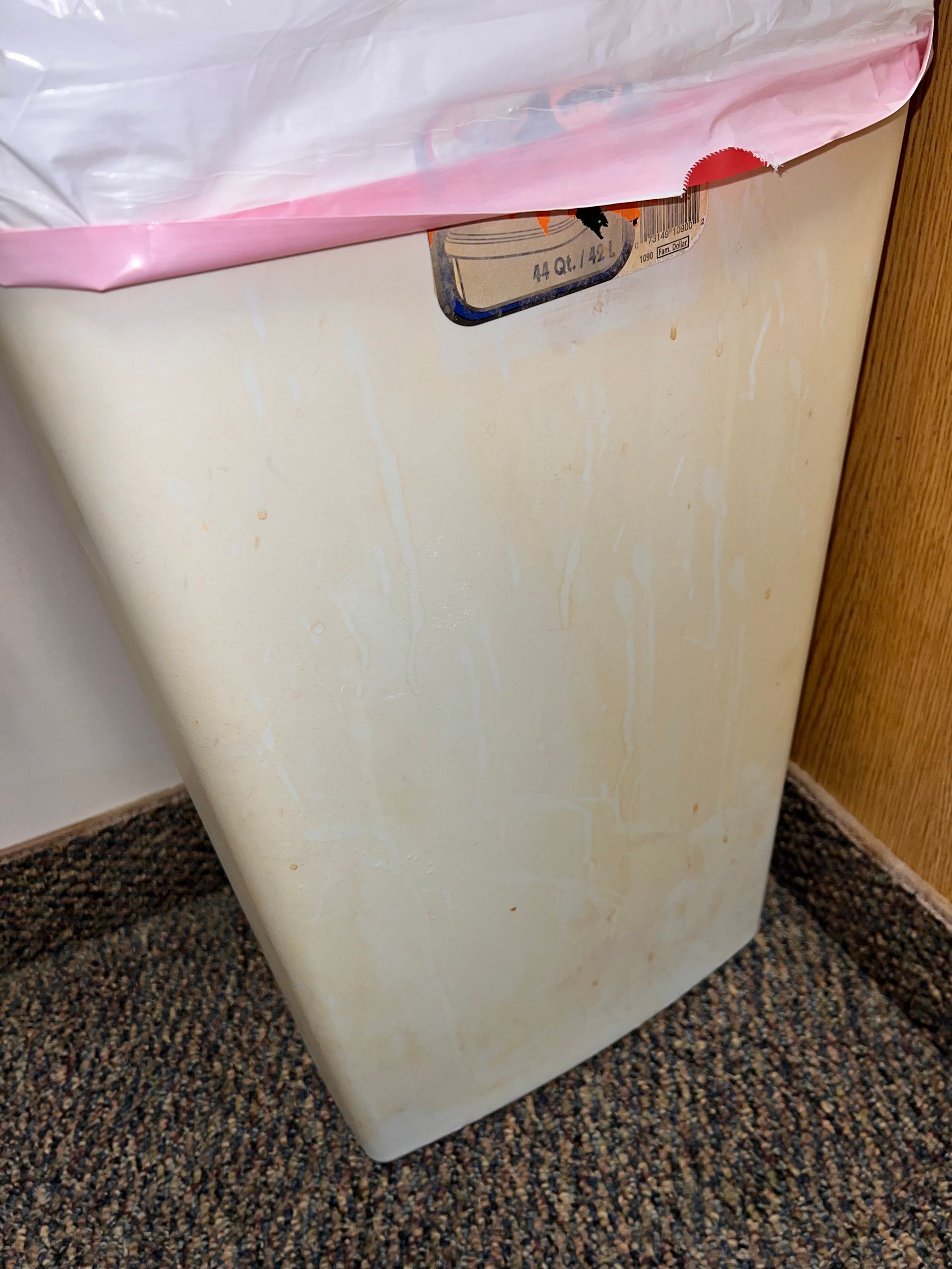 Beige trash can with a pink-rimmed trash bag on a carpeted floor. office cleaning Youngstown oh
