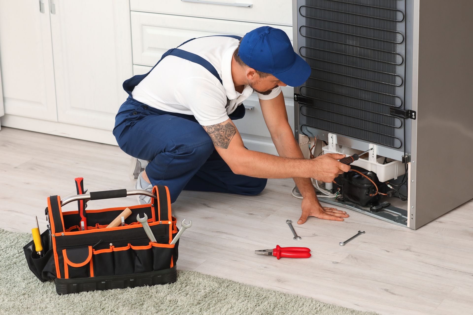 Refrigerator repairman working on the back of an appliance — Fast Tech Appliance Repairs in Newcastle, NSW