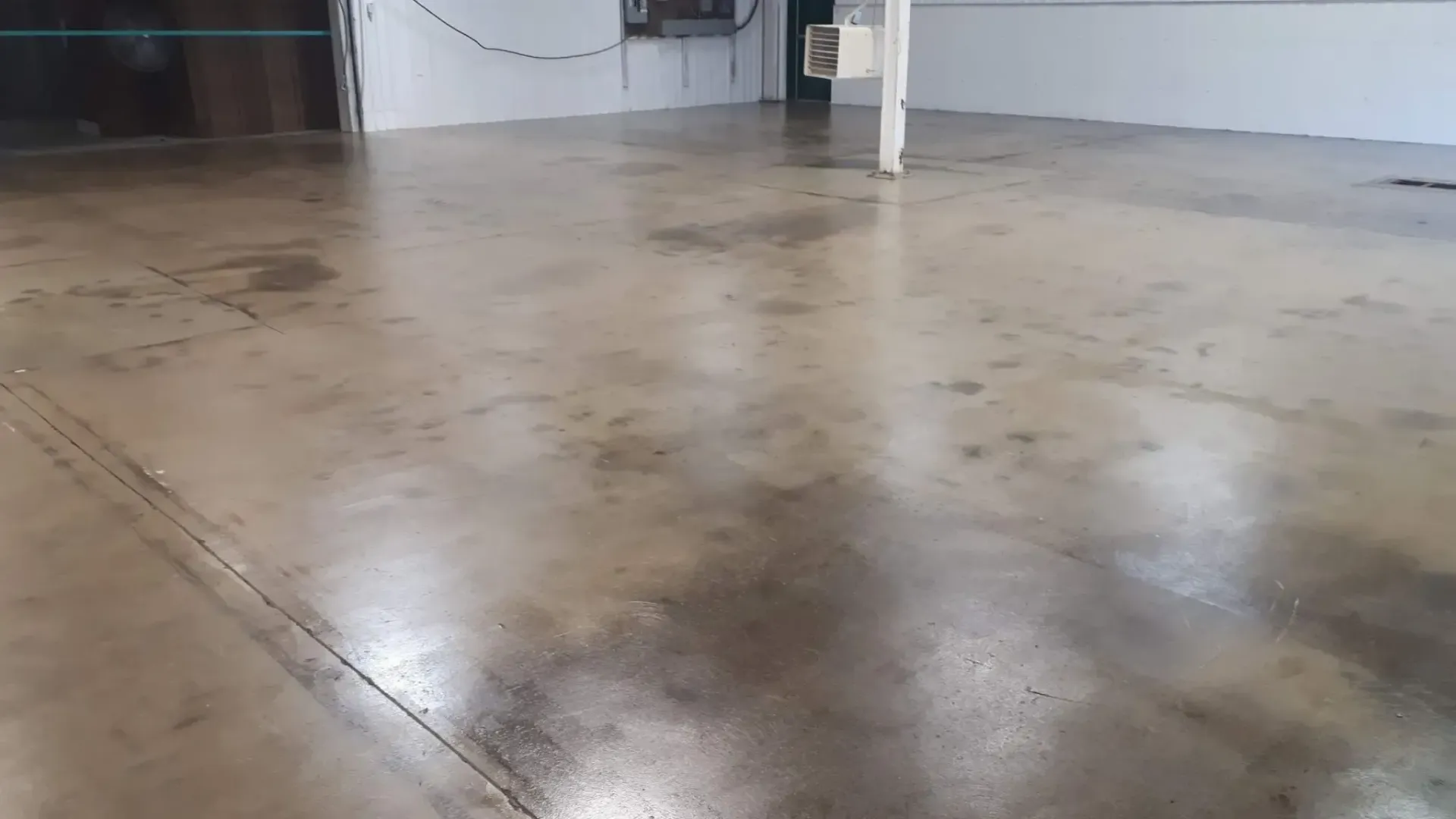 Polished concrete floor in a room. Reflections and color variations are visible on the surface.