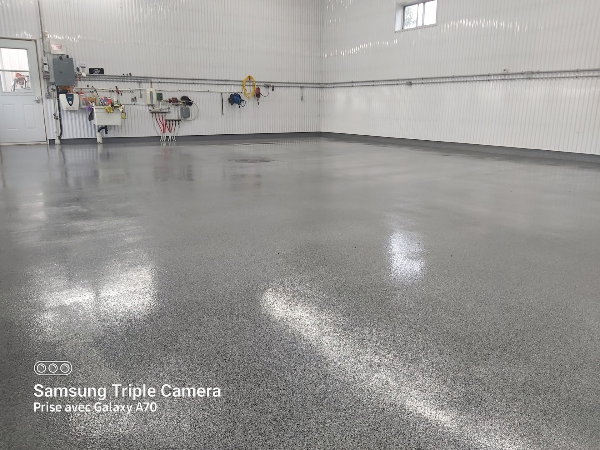 Gray epoxy floor in a large, bright room. Walls are white, with a few fixtures visible.