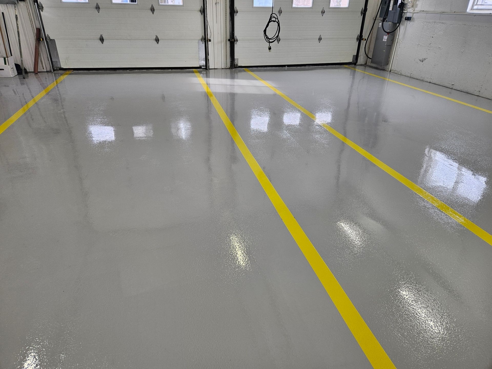 Gray industrial floor with yellow lines, near white garage doors.