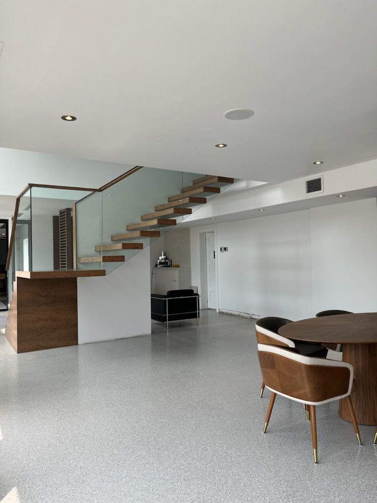 A living room with a staircase and a table and chairs