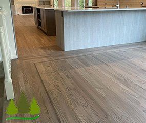 Hardwood floor installed with a perimeter border detail, next to a light wood kitchen island.