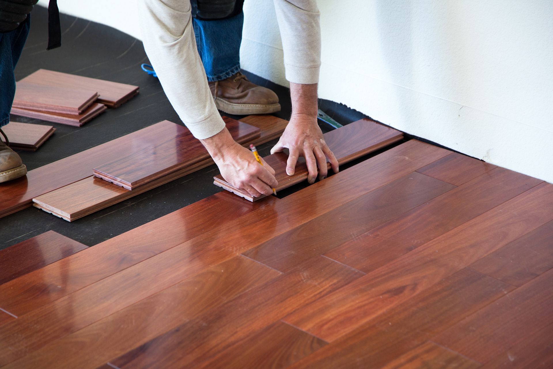 A worker is installing a hardwood floor.