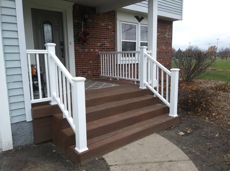 Front porch with brown steps, white railings, and a brick house entrance.