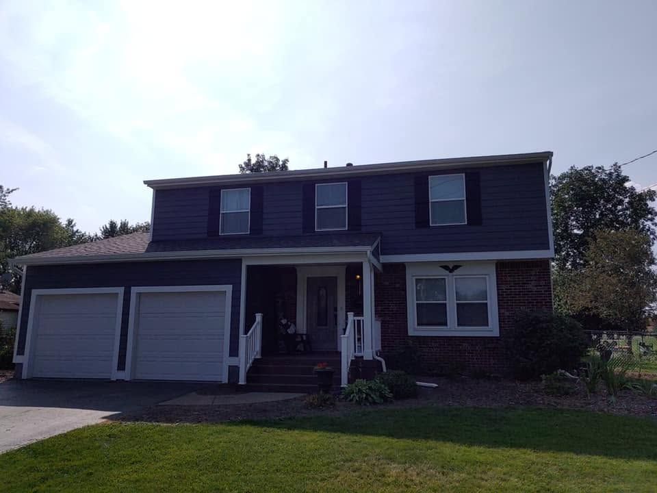 Two-story suburban house with a double garage and front porch on a sunny day