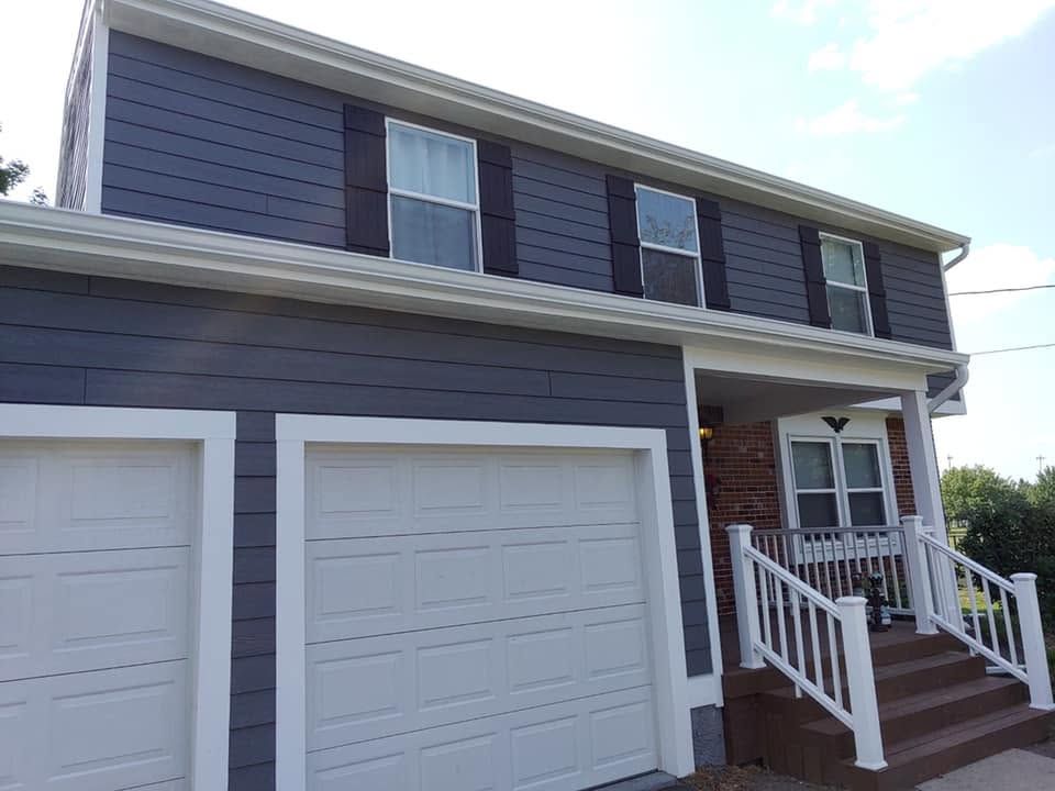 Two-story gray house with white trim, double garage, and front porch with stairs