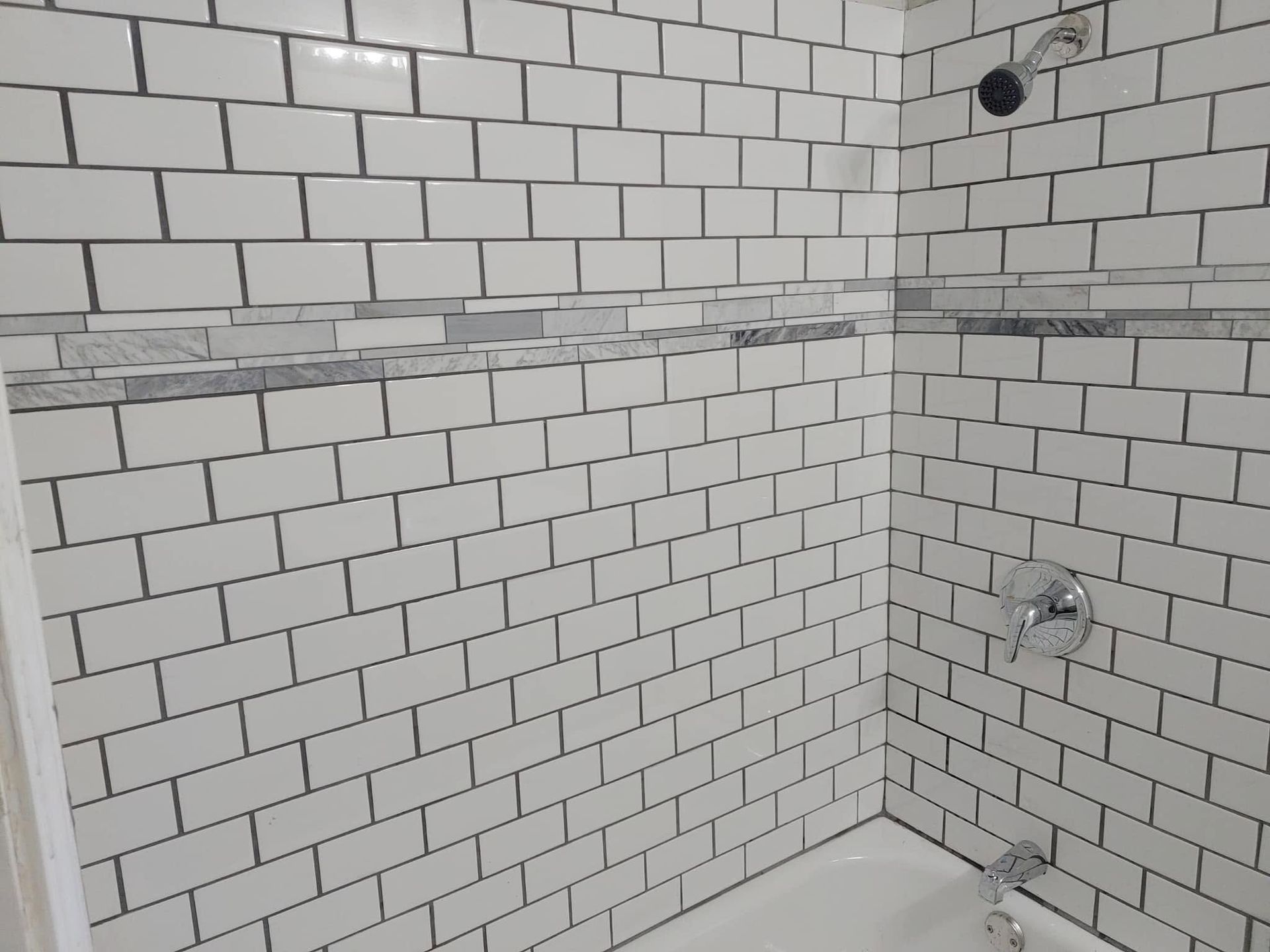 Empty tiled shower corner with plumbing fixtures and exposed wall seams