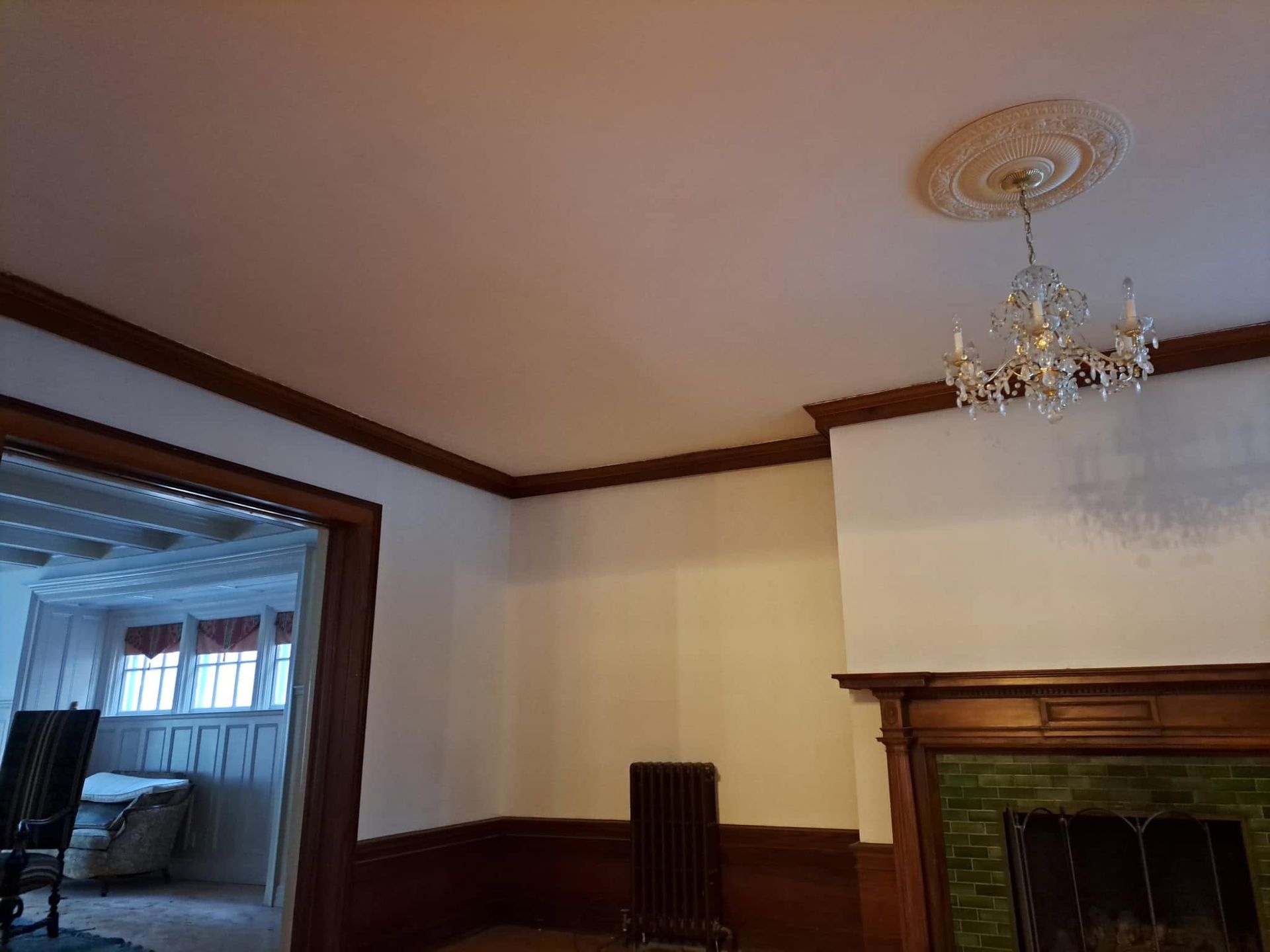 Living room with dark wood trim, fireplace, chandelier, and doorway to an adjoining room