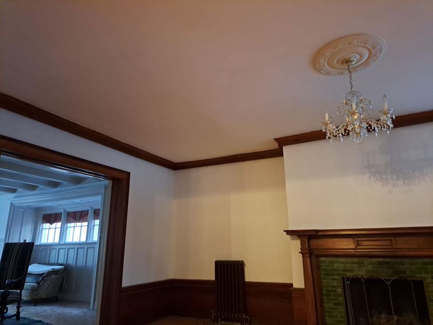 Interior room with wood trim, fireplace, chandelier, and doorway to a brighter adjoining room