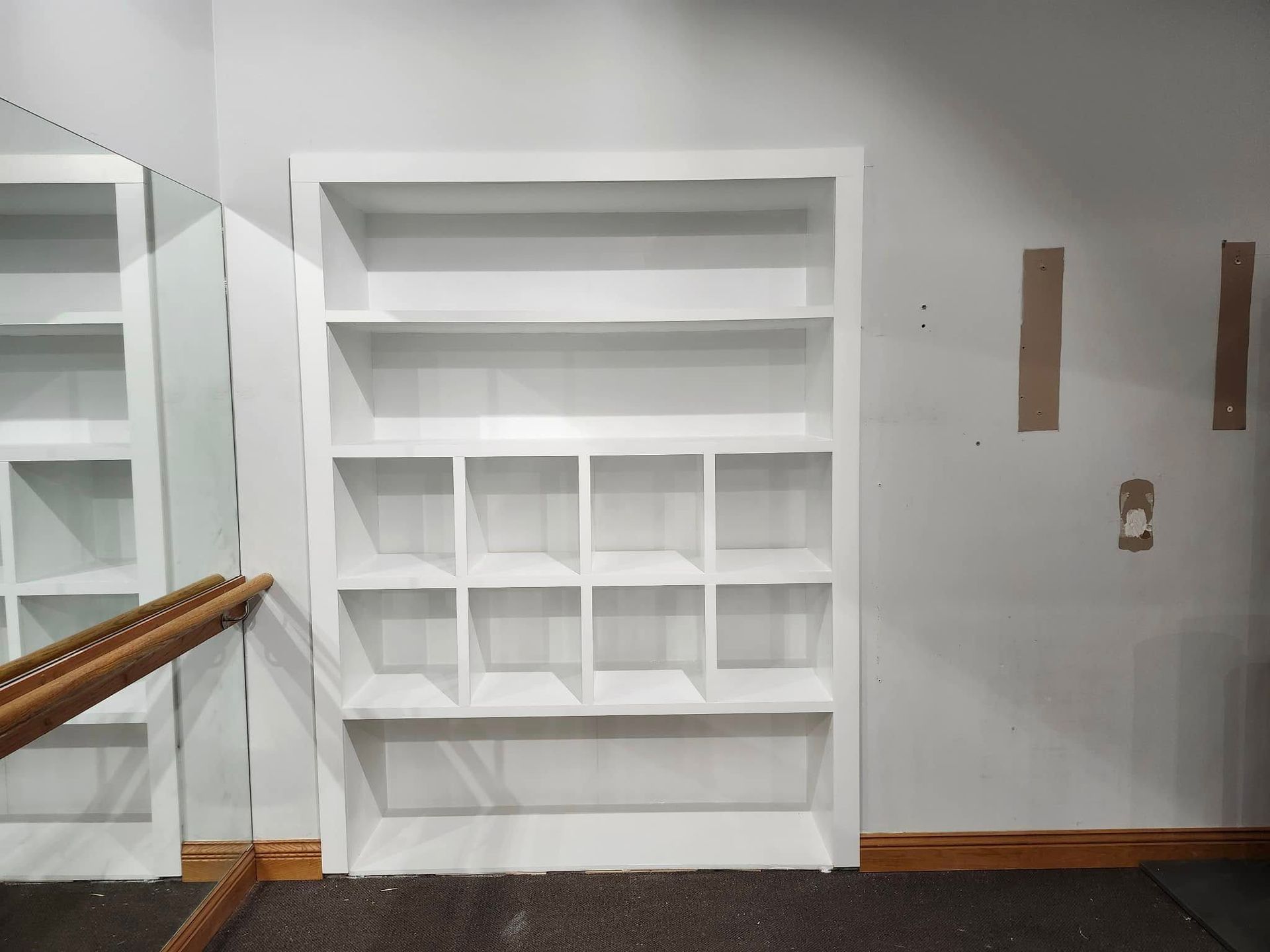 Built-in white shelving unit in a mostly empty room with light walls and wood trim.