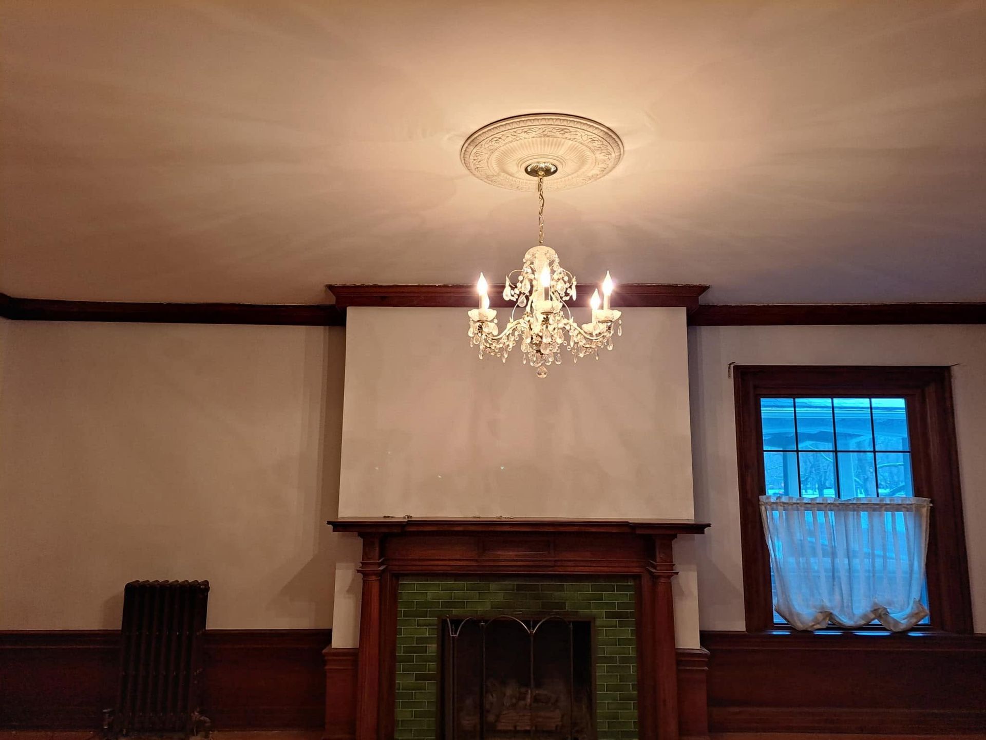 Elegant room with chandelier, fireplace, dark wood trim, and a blue-curtained window