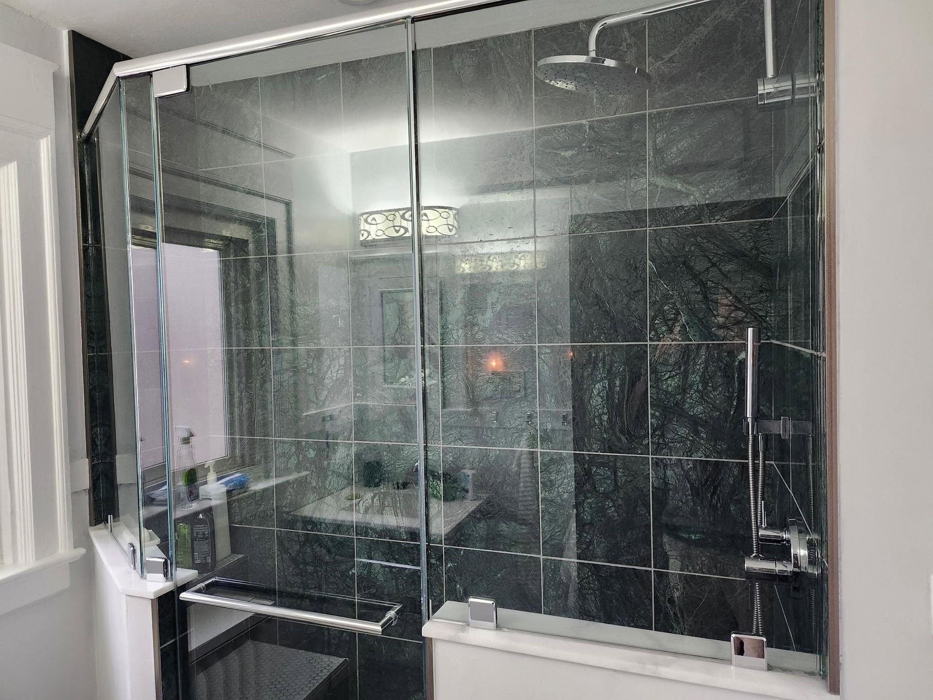 Modern bathroom with a glass shower enclosure and dark tile interior