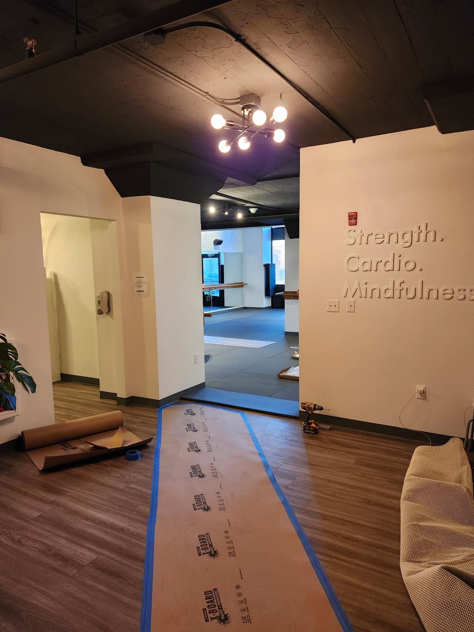 Modern office corridor with carpet runner, open doorway, and ceiling lights on a dark ceiling